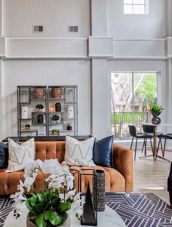 A living room with a brown sofa and a coffee table with a vase of flowers on it.