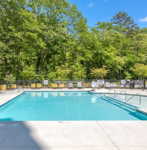 a swimming pool with a fence around it and trees in the background