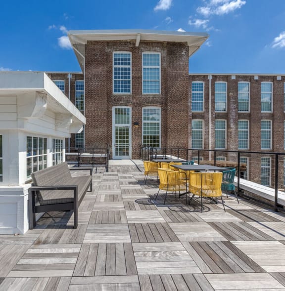 a large deck with tables and chairs in front of a building