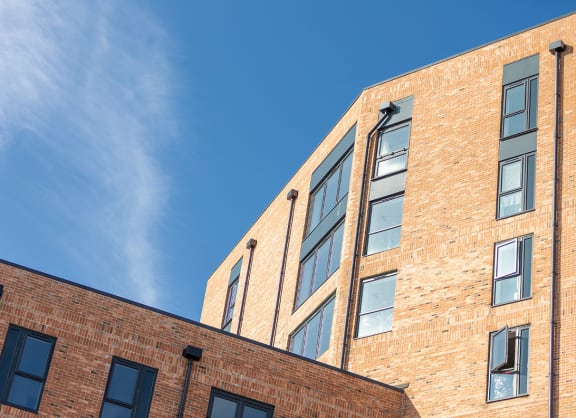 a view of two brick apartment buildings against a blue sky