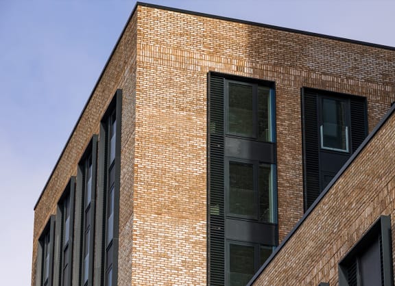 a view of two brick apartment buildings against a blue sky