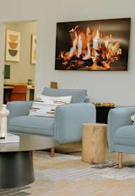 A living room with a fireplace and a painting of a fire on the wall.