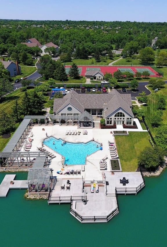 a mansion with a large pool in a grassy area next to a lake