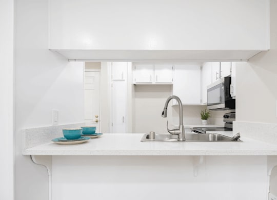 a white kitchen with a sink and a counter top at Huntington Terrace North Senior, California