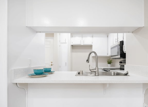 a white kitchen with a sink and a counter top at Huntington Terrace North Senior, California