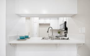 a white kitchen with a sink and a counter top at Huntington Terrace North Senior, California