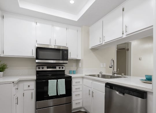 a kitchen with white cabinets and black and white counter tops at Huntington Terrace North Senior, Huntington Beach California