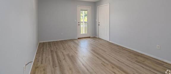 an empty living room with hardwood floors and a door to a patio