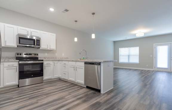 A kitchen with white cabinets and a wooden floor.