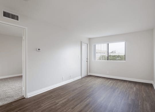 an empty living room with white walls and wood flooring at Huntington Terrace North Senior, Huntington Beach