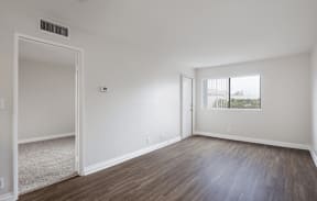 an empty living room with white walls and wood flooring at Huntington Terrace North Senior, Huntington Beach