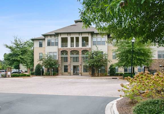 a large building with a driveway and trees in front of it