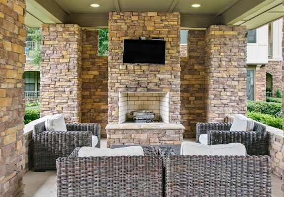 a patio with wicker furniture and a stone fireplace