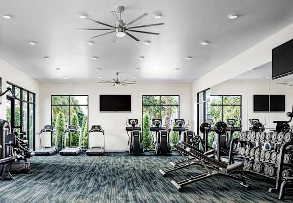 a gym with cardio machines and televisions on the wall
