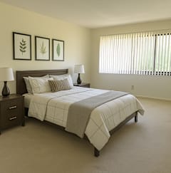 A bedroom with a bed, nightstands, and pictures on the wall.