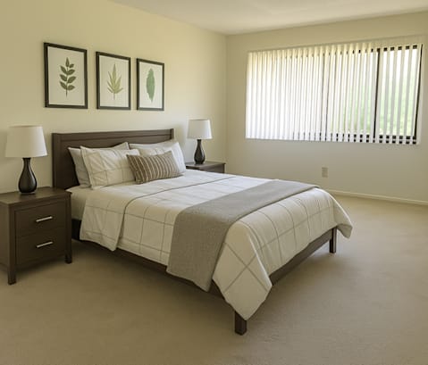 A bedroom with a bed, nightstands, and pictures on the wall.