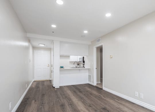 a living room and kitchen with white walls and wood flooring at Huntington Terrace North Senior, Huntington Beach, CA 92648