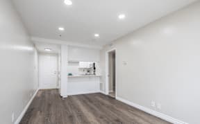 a living room and kitchen with white walls and wood flooring at Huntington Terrace North Senior, Huntington Beach, CA 92648