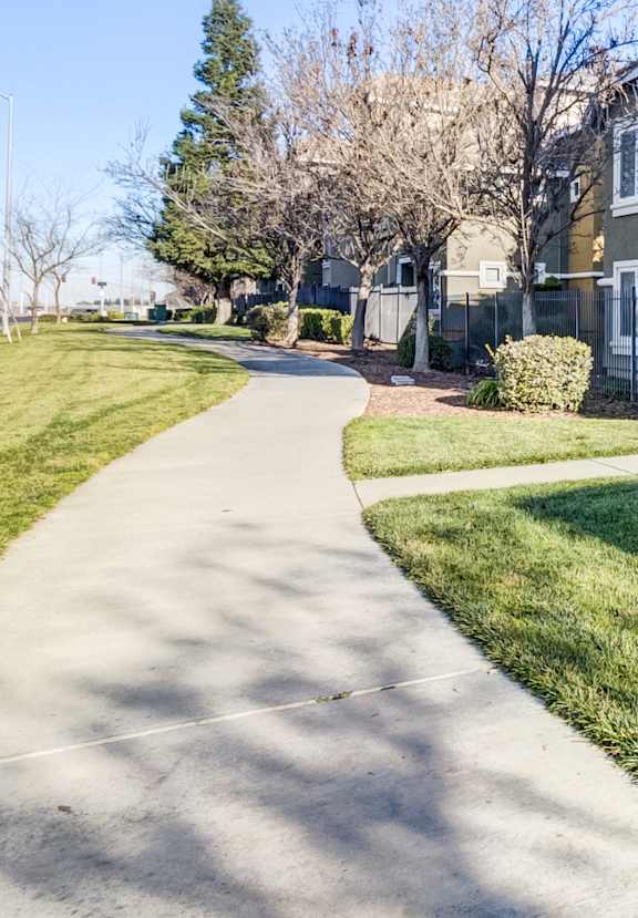 A residential building with a well-maintained lawn and a sidewalk.
