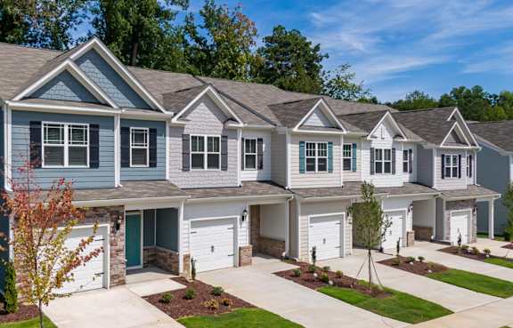 A row of houses with garages and driveways. at Ashford Townes Apartments, Fuquay-Varina, NC, 27526