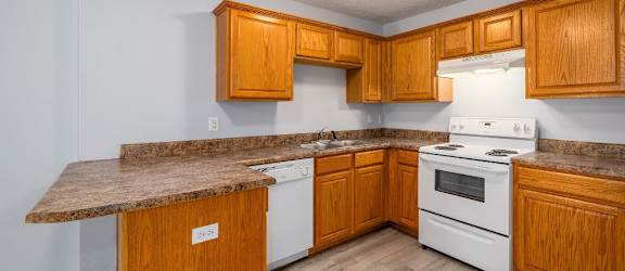 a kitchen with wooden cabinets and a white stove top oven