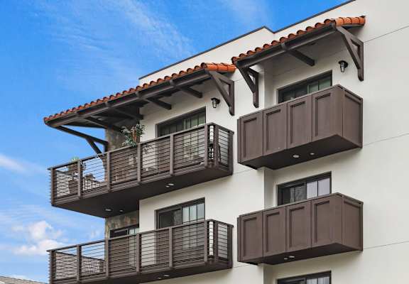 a white building with brown balconies and a blue sky