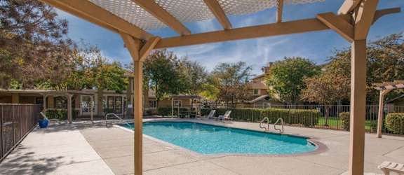 A wooden bench is in front of a pool.
