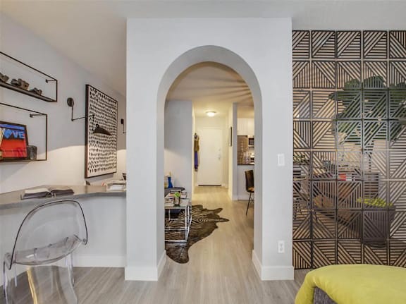 A hallway with a yellow bed on the right and a black and white patterned wall on the right.