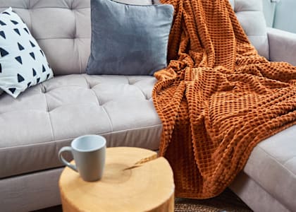 a couch with a blanket on it and a coffee table with a coffee mug on