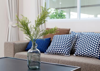 a couch with blue and white pillows and a glass vase with some flowers