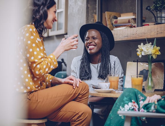 two women sitting at a table in a cafe talking