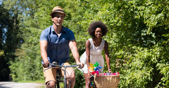 A man and a woman are riding bicycles on a road.