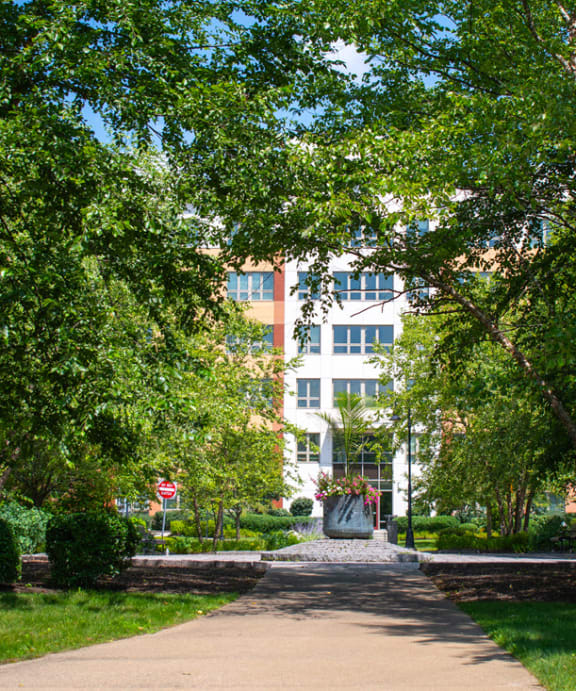 a large brick building with a driveway in the foreground and a parking lot in the background