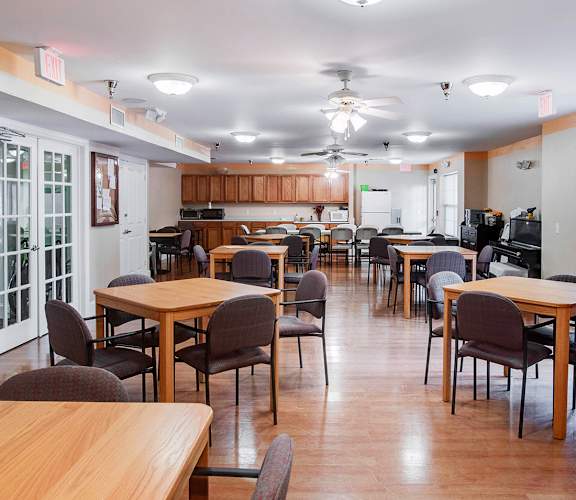 a dining room with tables and chairs and a kitchen in the background