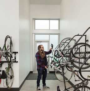 A man is standing in a room with a collection of bicycles.