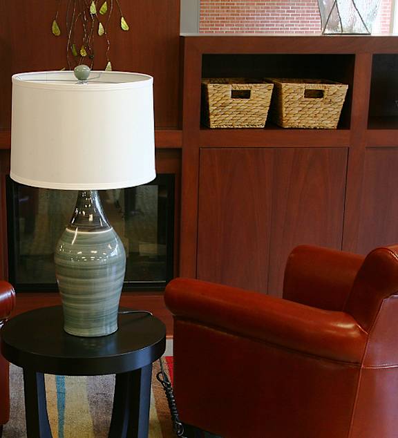 A yellow mug sits on a coffee table in front of a grey couch with a yellow pillow and a white blanket.