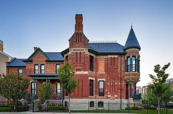 a red brick house with a turret and a fence