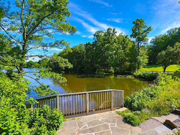 A serene park with a lake, trees, and a stone walkway. at Charlestowne North Apartments, Maryland