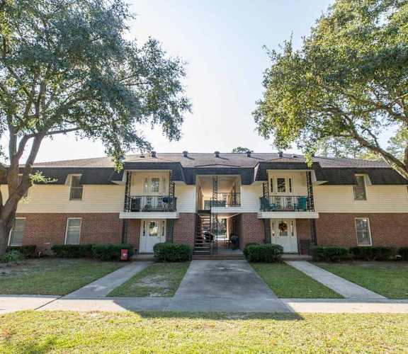 A two-story apartment building with a front lawn and trees.