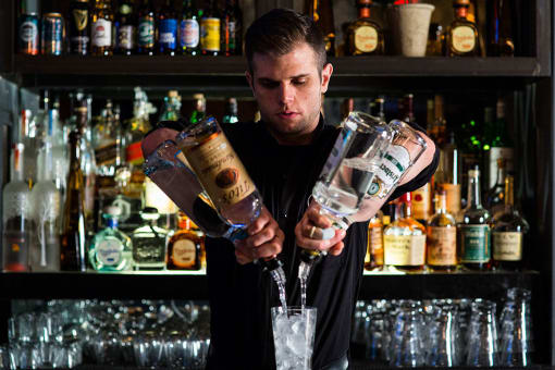 a bartender pours a drink from a cocktail shaker into a glass at Aertson Midtown Apartments, 905 20th Avenue South, Nashville