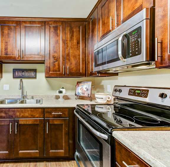 A kitchen with dark wood cabinets and black appliances.