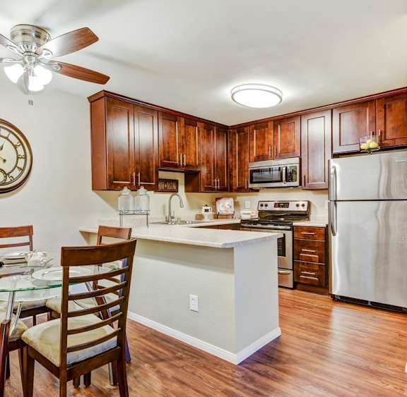 A kitchen with a table and chairs and a clock on the wall.