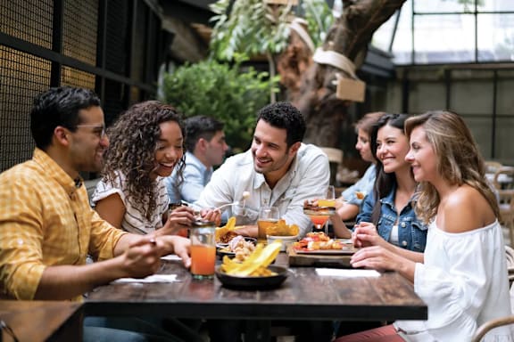 A group of people are sitting around a table eating food and drinking juice.