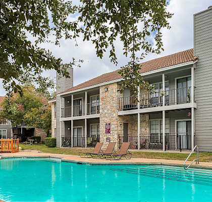 our apartments offer a swimming pool and a patio with lounge chairs at The Broadwater at Salado Creek, San Antonio, Texas