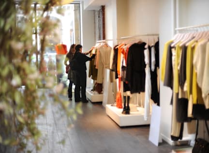 A woman is shopping for clothes in a brightly lit store.