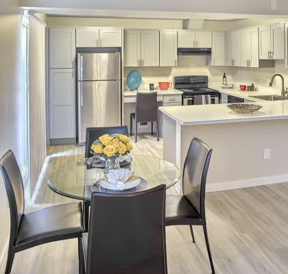 a kitchen with white cabinets and a white counter top and a glass table with black chairs  at 3030 Lake City, Seattle, WA