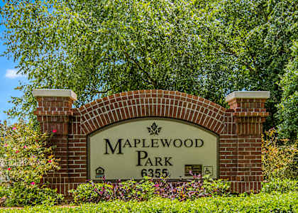 a sign that says maplewood park with trees in the background