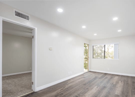 an empty living room with white walls and wood flooring at Huntington Terrace North Senior, Huntington Beach, CA
