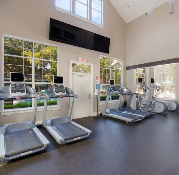 a gym with cardio equipment and a flat screen tv