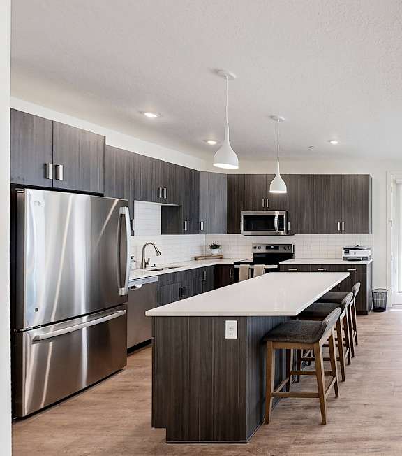 A modern kitchen with a long island and bar stools.